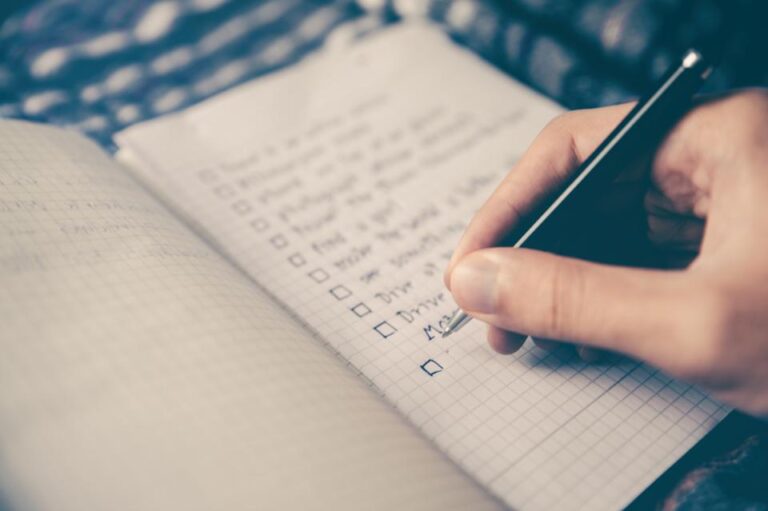 Hand writing and checking off a personal goals checklist, illustrating keeping promises to yourself