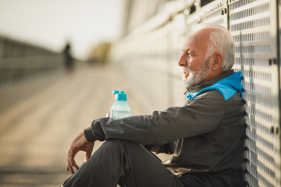 Older man resting with a water bottle after exercise, illustrating rest and energy recovery