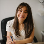 A smiling woman writing specific, genuine entries in her gratitude journal