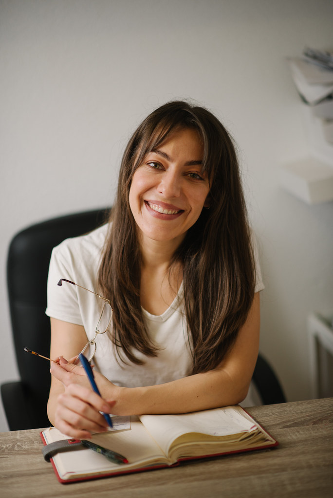 A smiling woman writing specific, genuine entries in her gratitude journal